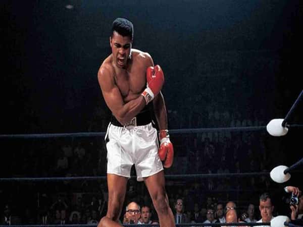 Ali đứng trong sàn boxing cùng đai vô địch biểu tượng của quyền lực, khí chất